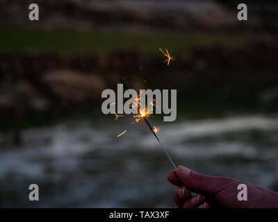 Un irriconoscibile persona con un sparkler sfrigolanti in mano Foto Stock