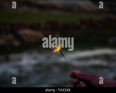 Un irriconoscibile persona con un sparkler sfrigolanti in mano Foto Stock