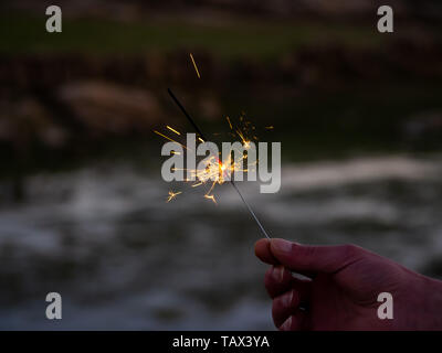 Un irriconoscibile persona con un sparkler sfrigolanti in mano Foto Stock