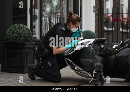 Controllo di polizia un ciclomotore al di fuori delle ore di casa sulla Duke Street, Westminster, dove ciclomotore-riding rapinatori di mira la luxury watch shop, rendendo con gli oggetti rubati dal fracassato vetrina. Foto Stock