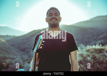 Uomo a suonare la chitarra sulle montagne Foto Stock