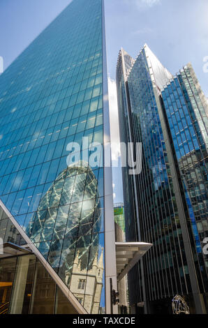 Il Gherkin è visto in una riflessione int egli lato del bisturi nel quartiere finanziario della City di Londra, Regno Unito Foto Stock