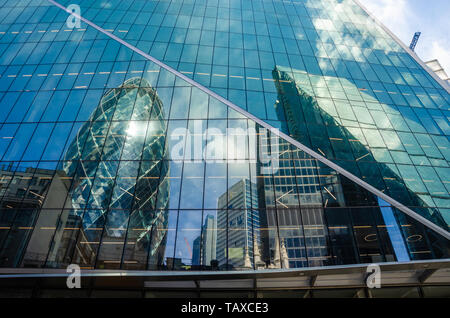 Il Gherkin è visto in una riflessione int egli lato del bisturi nel quartiere finanziario della City di Londra, Regno Unito Foto Stock