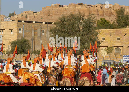 I cammelli e piloti del confine indiano sicurezza Force condurre una processione attraverso il quartiere storico durante il desert festival in Jaisalmer, India Foto Stock