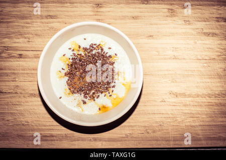 Una sana prima colazione - ciotola di porridge con cannella, sciroppo d'acero e semi di lino Foto Stock