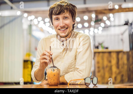 Uomo di bere freddo tè bolla in cafe Foto Stock