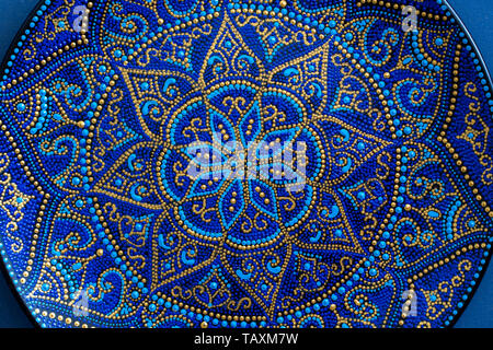 Decorativa piastra in ceramica con blu e colori dorati, tavole dipinte, vicino. Decorativo La piastra di porcellana dipinta con vernici acriliche, artigianato Foto Stock