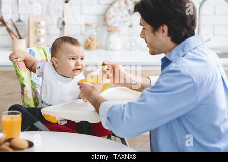 Papà alimentando il suo bambino con cibo sano Foto Stock