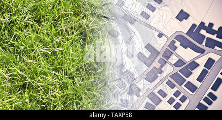 Dalla natura per una nuova città - Concetto di immagine con un verde prato che sfuma sulla mappa di una città immaginaria con edifici e strade - la natura diventa Foto Stock