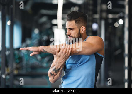 Uomo sportivo in palestra facendo esercizi di stretching per le mani Foto Stock