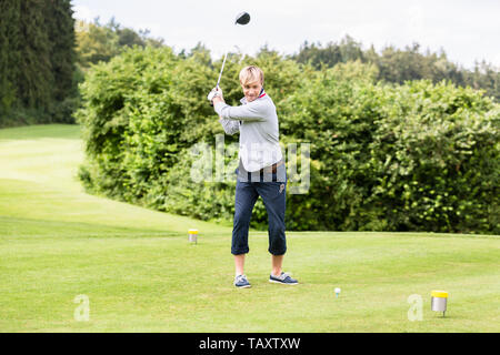 Ritratto di maschio giocatore di golf in un colpo mentre si sta in piedi sul campo da golf Foto Stock