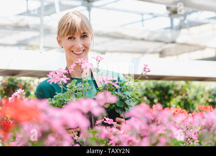 Giardiniere donna nella sua serra con fiori per la vendita Foto Stock