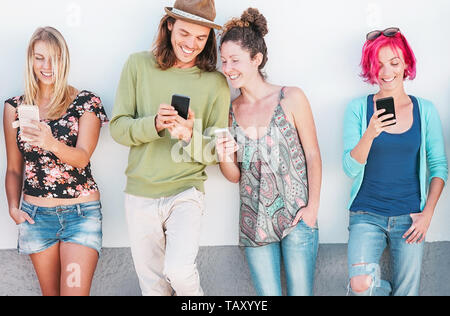 Happy amici guardando sul loro smart cellulari outdoor - Giovane generazione divertirsi con la nuova tecnologia e social network Foto Stock