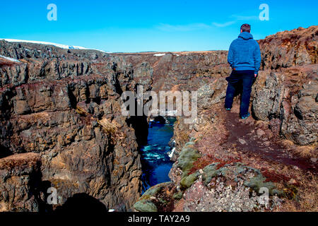 L'uomo guarda una gola causando un fiume di fluire in inverno di Islanda Foto Stock