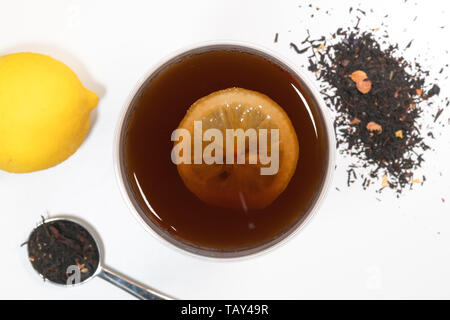 Limone tazza da tè vista superiore con fettina di limone e frutta e foglie di tè in background Foto Stock
