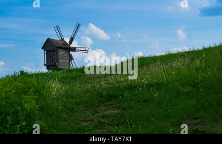 Vecchio mulino in piedi da solo nel campo con il cielo azzurro sullo sfondo con copyspace Foto Stock