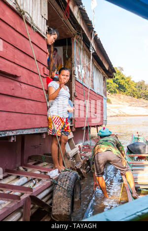 Il fiume Mekong, Laos, Feb 2016: famiglia laotiane guardando oltre il recinto e lo scarico di cose da loro nave galleggiante house. Foto Stock