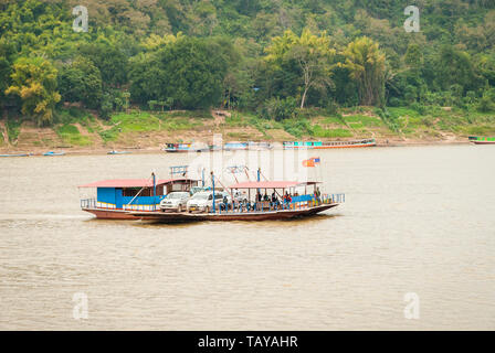 Luang Prabang, Laos - Feb 2016: traghetto locale zattera il trasporto di automobili, motociclette e persone oltre il Fiume Mekong Foto Stock