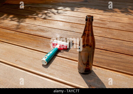 Vuoto bottiglia di birra e una spazzola sono giacenti sulla mezza terrazza rientrante con smalto Foto Stock