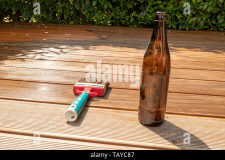 Vuoto bottiglia di birra e una spazzola sono giacenti sulla mezza terrazza rientrante con smalto Foto Stock