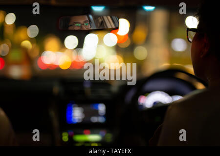 Donna alla guida di auto con bokeh luci dal traffico di notte tempo. Foto Stock