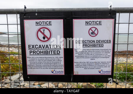 Cartelli di avvertimento divieto di rilevamento di metallo e di scavo vicino alla spiaggia nel piccolo porto di pesca di Kilmore Quay, Co Wexford, Irlanda meridionale. Foto Stock