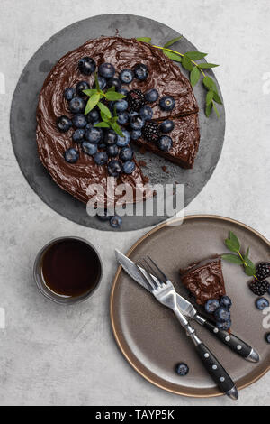 Piano tavolo pezzo di torta al cioccolato con tutta la torta su sfondo grigio chiaro. Concetto di vacanza cibo dolce Foto Stock