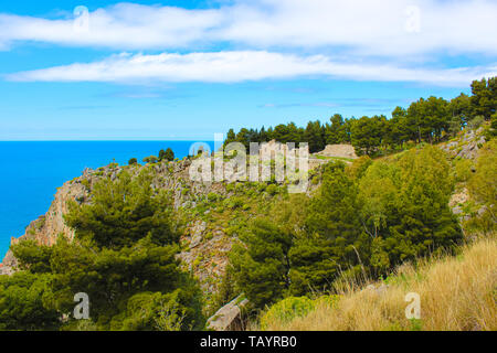 Rovine della Rocca di Cefalù sulla roccia che si affaccia sulla costa tirrenica in Cefalu, Sicilia, Italia. Resti del castello medievale sono circondati dal verde degli alberi. Foto Stock