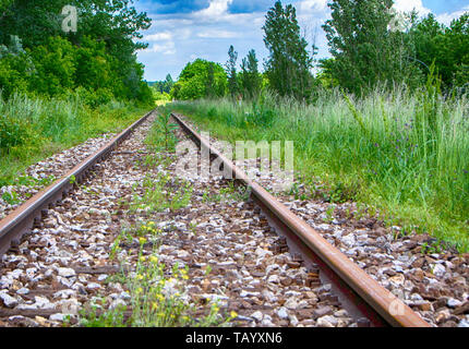 Abbandonati i binari della ferrovia. Foto scattata sulla giornata soleggiata con soffici nuvole. - Immagine Foto Stock