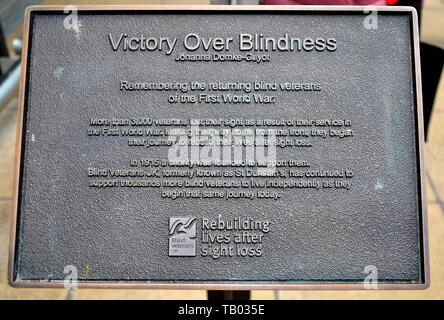 Il bando di gara che descrive la statua di sette soldati cieco - vittoria sulla cecità - all'ingresso della stazione ferroviaria di Manchester Piccadilly, Regno Unito Foto Stock