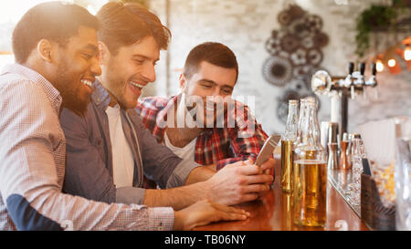 Notizie di condivisione con lo smartphone e bere la birra nel bar Foto Stock