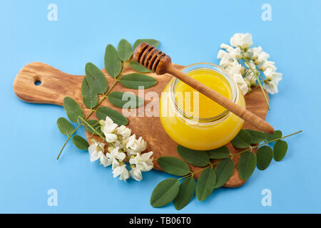 Il miele di fiori d'acacia su sfondo blu Foto Stock