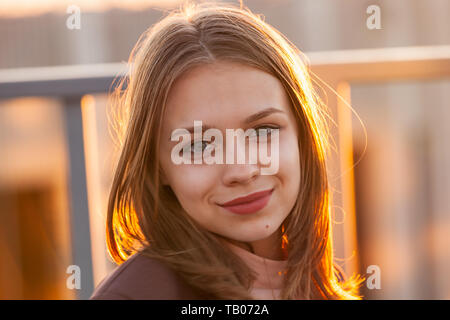 Bella sorridente ragazza adolescente, chiudere fino all'aperto verticale con retro-illuminato dalla luce del sole Foto Stock