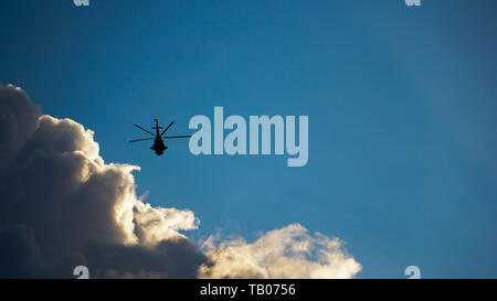 Silhouette di un grosso elicottero in volo contro il drammatico Cielo e nubi Foto Stock