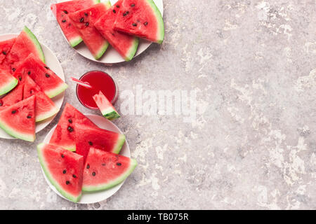 Fette di cocomero e succo di frutta su uno sfondo grigio, vista dall'alto Foto Stock