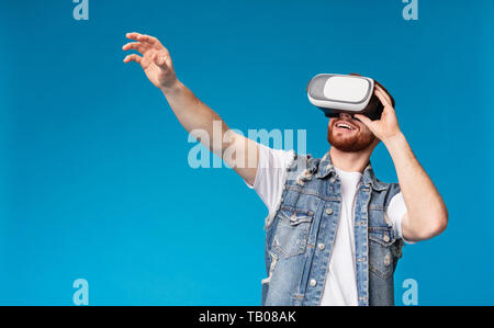 Allegro uomo cercando occhiali vr in studio Foto Stock