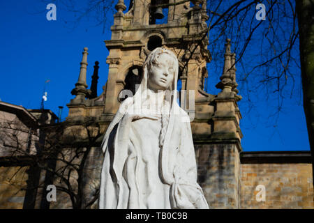 Bilbao, Spagna. Febbraio 13, 2019. Vergine Maria scultura con la San Vicente de Abando chiesa in background Foto Stock