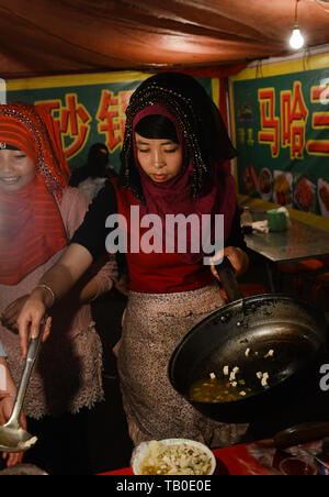 Hui donne musulmane la cottura al vivace mercato notturno in Linxia, Cina. Foto Stock