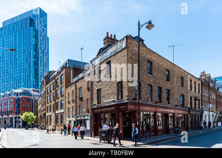 London, Regno Unito - 14 Maggio 2019: inglese antico ristorante di fronte Spitalfields Market contro il grattacielo della città di Londra Foto Stock