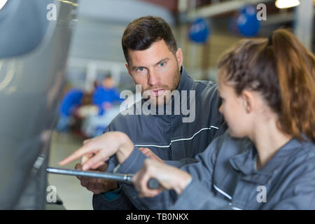 Consulenza meccanico apprendista femmina serraggio dadi ruote Foto Stock