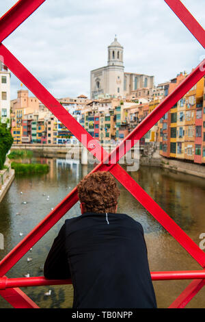 Uomo che guarda a vista dal ponte di Eiffel (Pont de les Peixateries Velles) sopra il fiume Onyar presso la Cattedrale di Girona e multi case colorate in giro Foto Stock