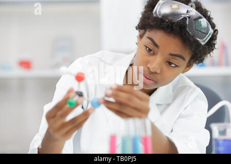 Donna assistente di laboratorio guarda al modello di DNA Foto Stock