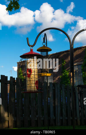 Gli alimentatori di Uccelli nel giardino con il cielo blu e nuvole in background. Foto Stock