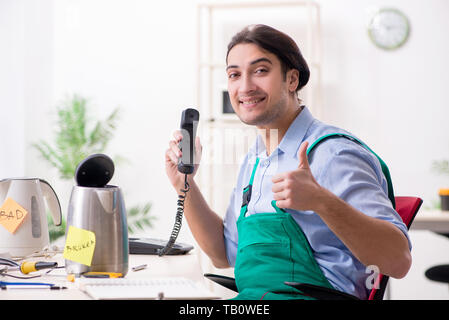 Giovane uomo che ripara il bollitore in centro di servizio Foto Stock