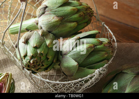 Cestello con carciofi crudi su tavola Foto Stock