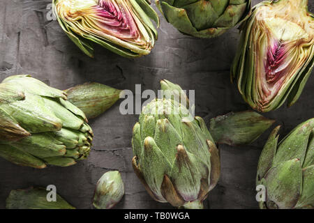 Carciofi crudi su sfondo grigio Foto Stock