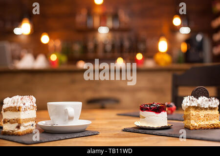 Insieme di diverse torte e dolci appena cotti disposti su un tavolo di legno. Deliziosa torta con frutta naturale sulla parte superiore. Tazza di caffè. Fetta di torta con biscotto sulla parte superiore. Foto Stock