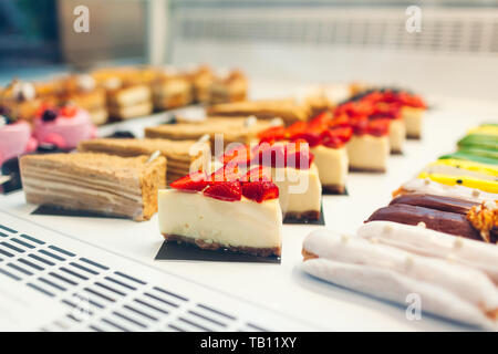 Assortimento di torte diverse su cafe vetrina. La varietà di sapori. Cioccolato e torte di panna in negozio con frutta e gelatina. Foto Stock