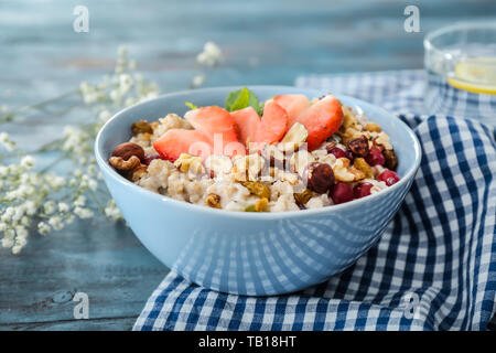 Ciotola con gustosi fiocchi d'avena sul tavolo di legno Foto Stock