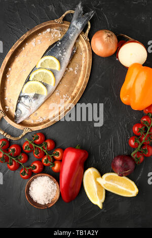 Vassoio con gustosa spigola pesce e verdure su sfondo scuro Foto Stock